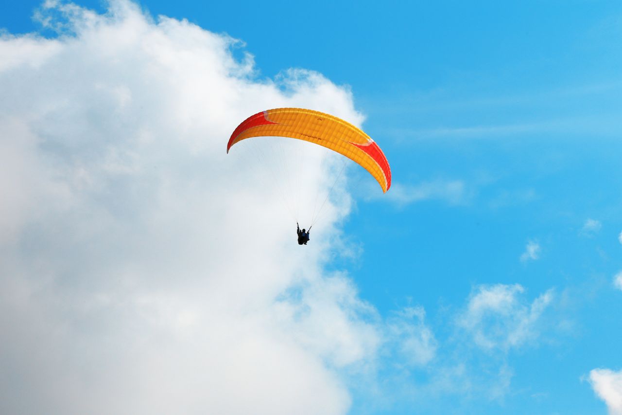 A thrilling paragliding experience captured against a vivid blue sky with clouds.