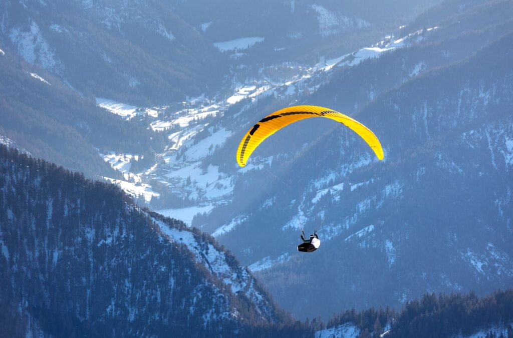 Experience the thrill of paragliding over the scenic, snow-covered Dolomites in Trentino-South Tyrol, Italy.