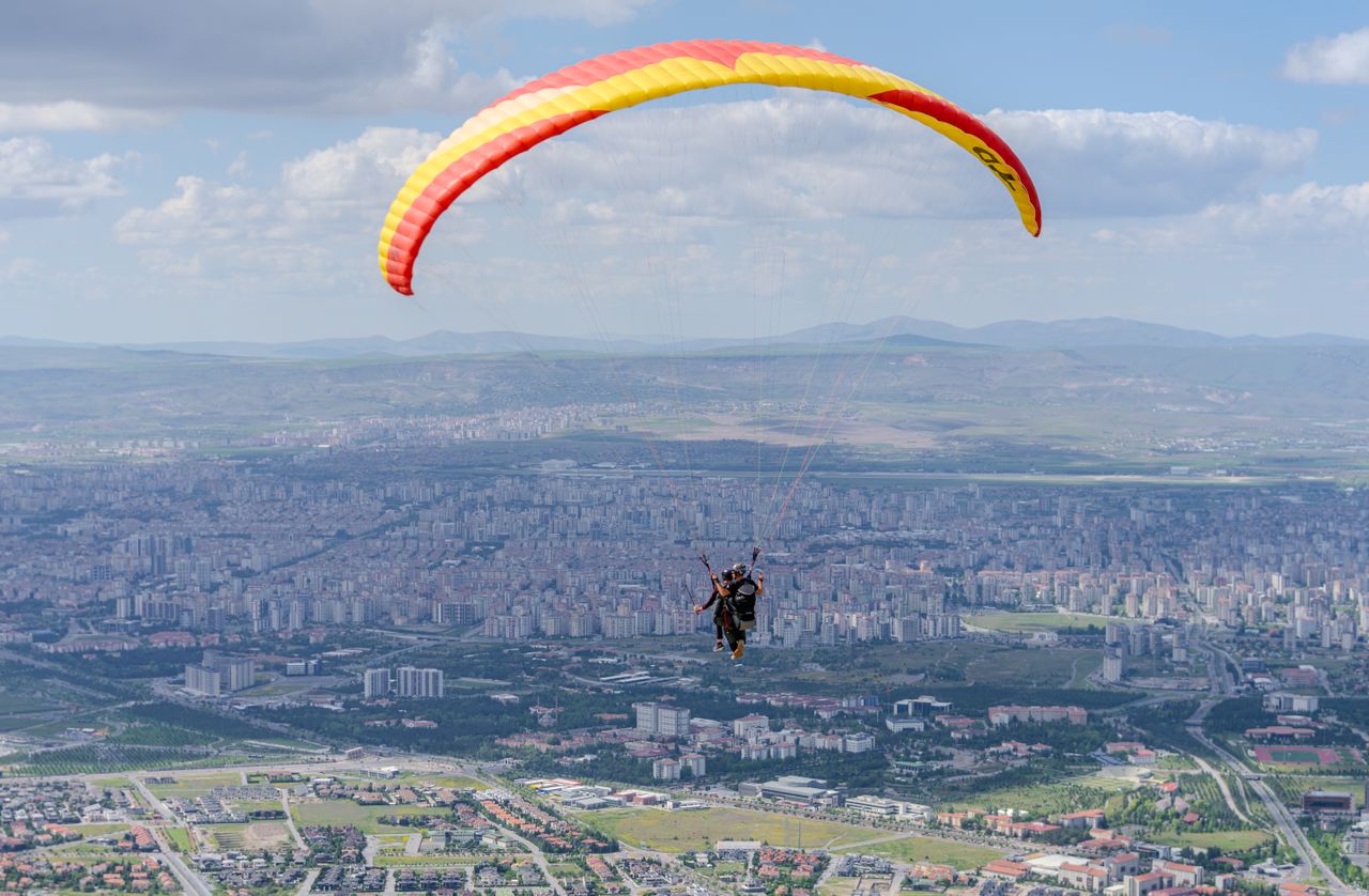 Paraglider soaring high above the cityscape of Kayseri, Türkiye on a clear day.