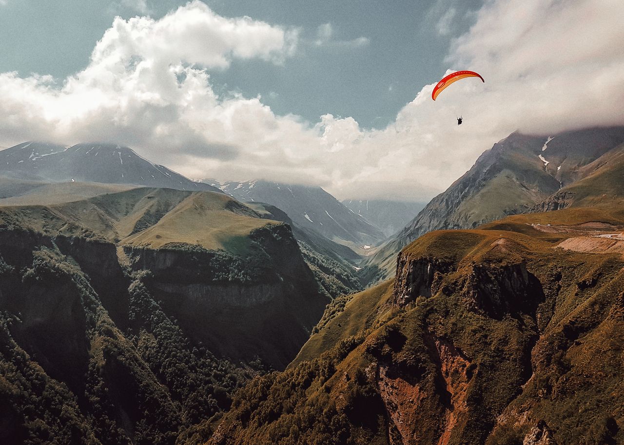 Scenic view of a paraglider soaring over the majestic mountains of Alagirsky District, Russia.